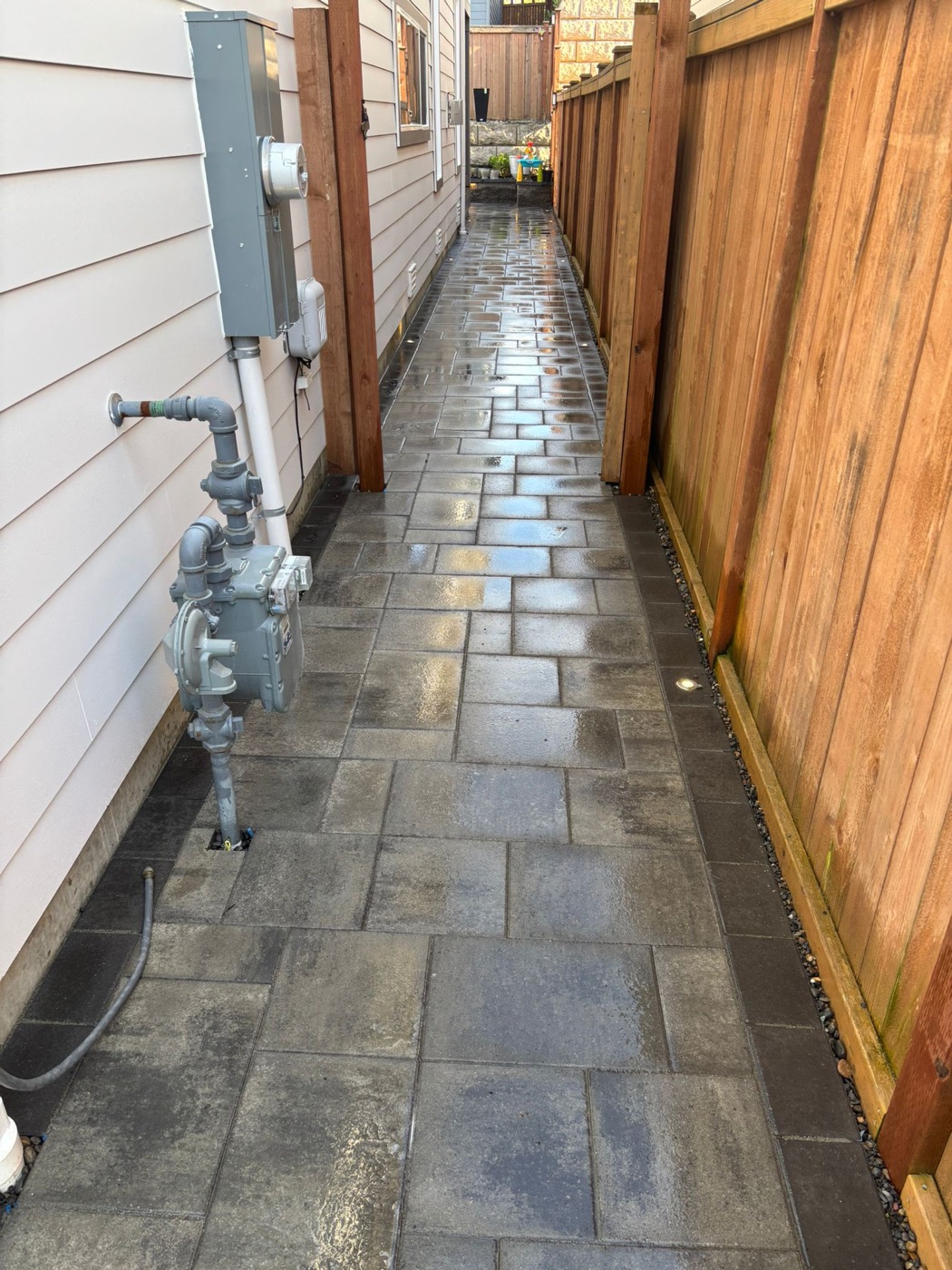 Side yard paver walkway with wood fence and landscape stones