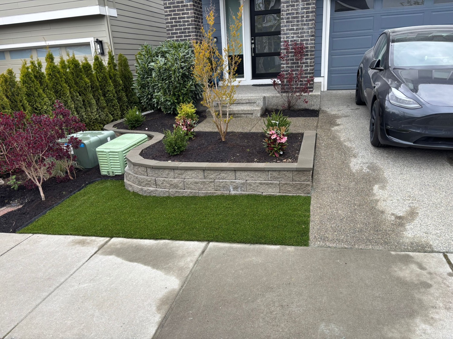 Front yard planting bed with stone border, turf, and shrubs